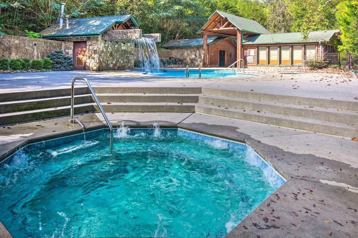 This exterior shot features both a hot tub and a sparkling swimming pool, framed by lush greenery and a lodge-style building. The inviting scene suggests opportunities for both relaxation and play, with spaces to gather, soak, or swim—echoing the section’s mention of resort-style amenities for couples seeking a blend of seclusion and activity.
