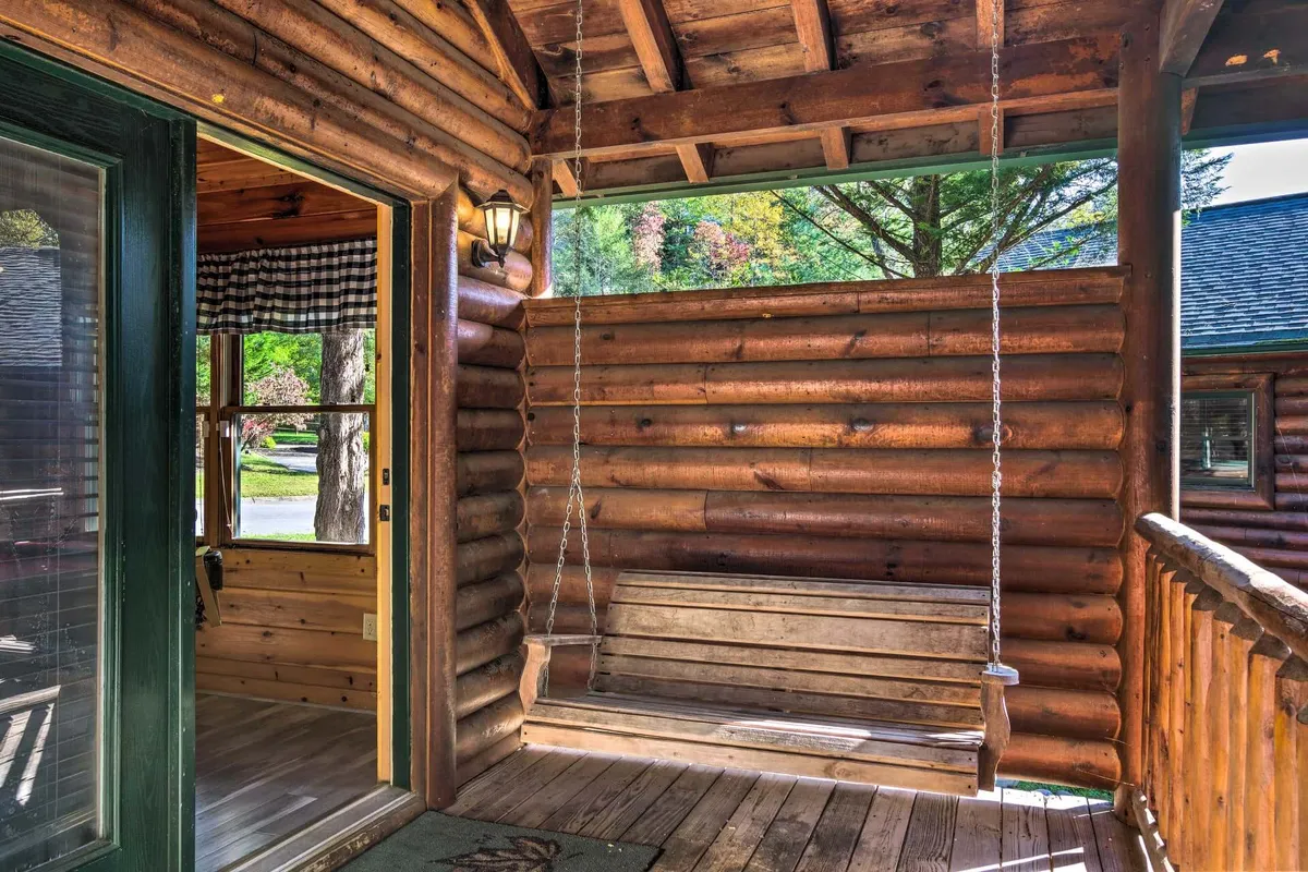 A cozy wooden swing set against the log cabin walls, with a doorway visible. The scene evokes a sense of tranquility and leisure, perfect for unwinding after a day of mountain activities, enjoying views, or sharing stories with loved ones.